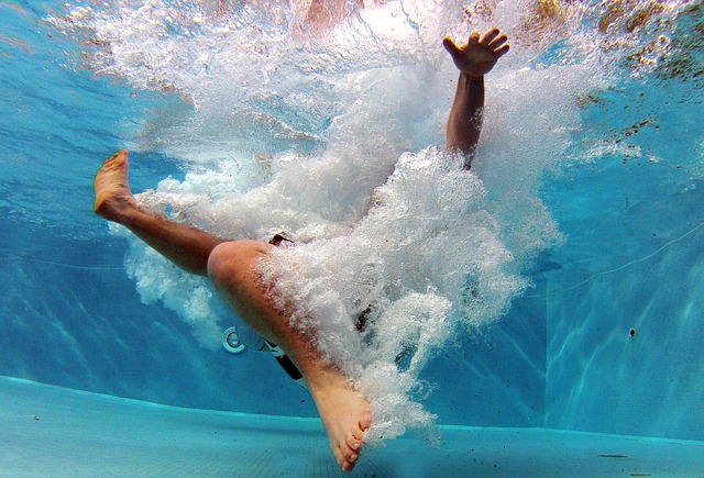Záběr na plavce ze dna bazénu